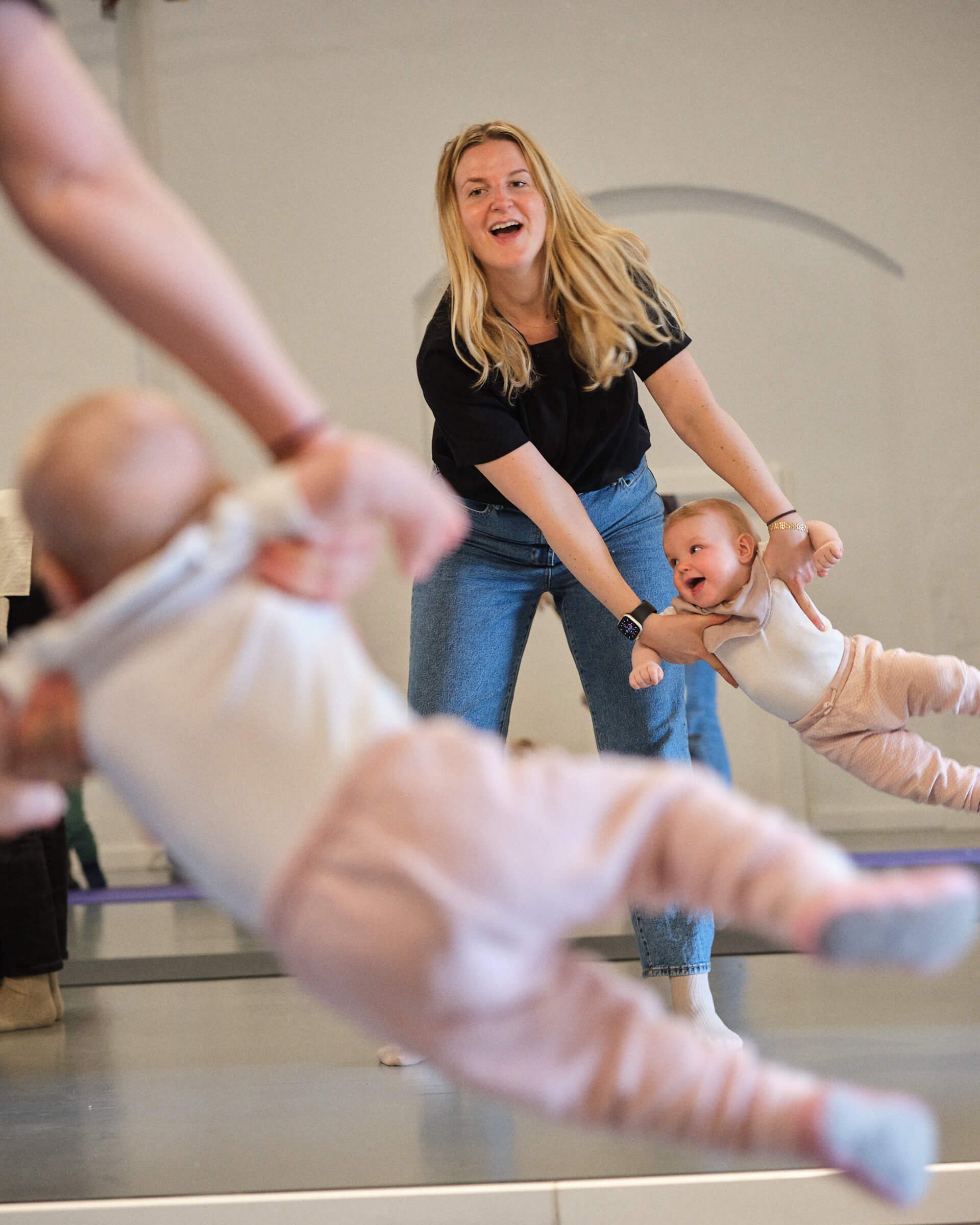 Glad mor står foran spejl og svinger sin baby frem og tilbage som griner af glæde.